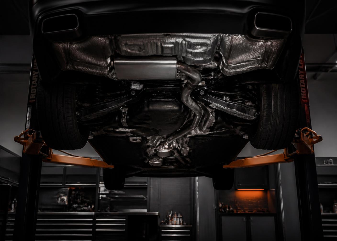 Vehicle undercarriage on a lift with exhaust piping visible